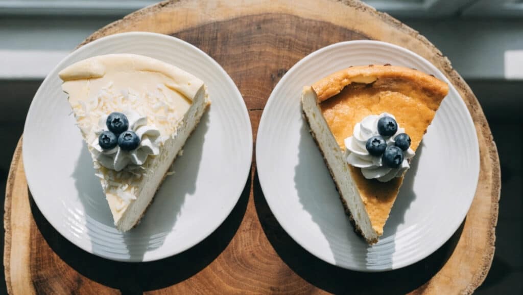 sernik na zimno z mascarpone obok klasycznego sernika pieczonego na drewnianej desce